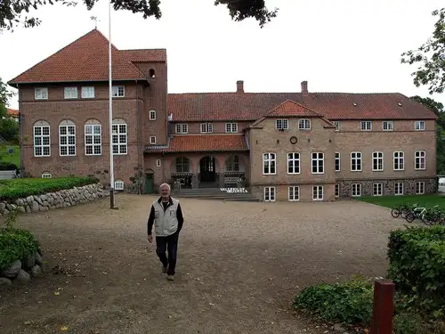Vallekilde H&oslash;jskoles hovedbygning tegnet af Andreas Bentsen 1876 og Martin Nyrop 1907, i forgrunden eftermiddagens rundviser Bent Larsen